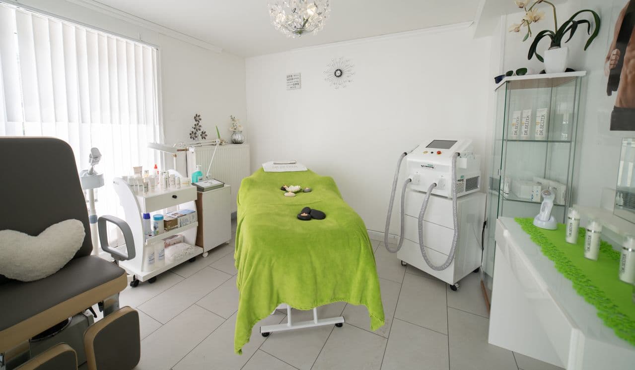Illustrative clinic treatment room with a green-covered treatment bed and equipment.