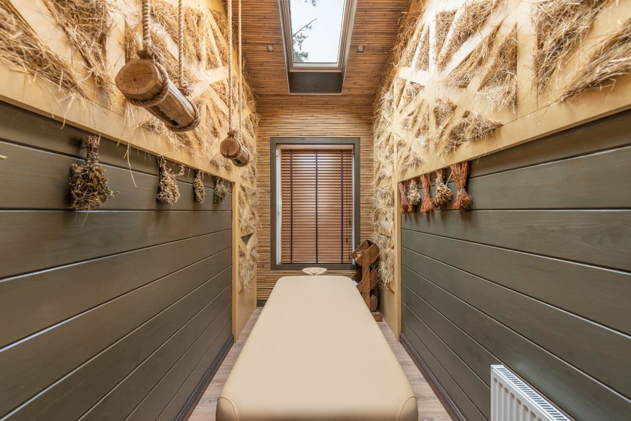 Massage table in a narrow, wood-paneled spa treatment room beneath a skylight.