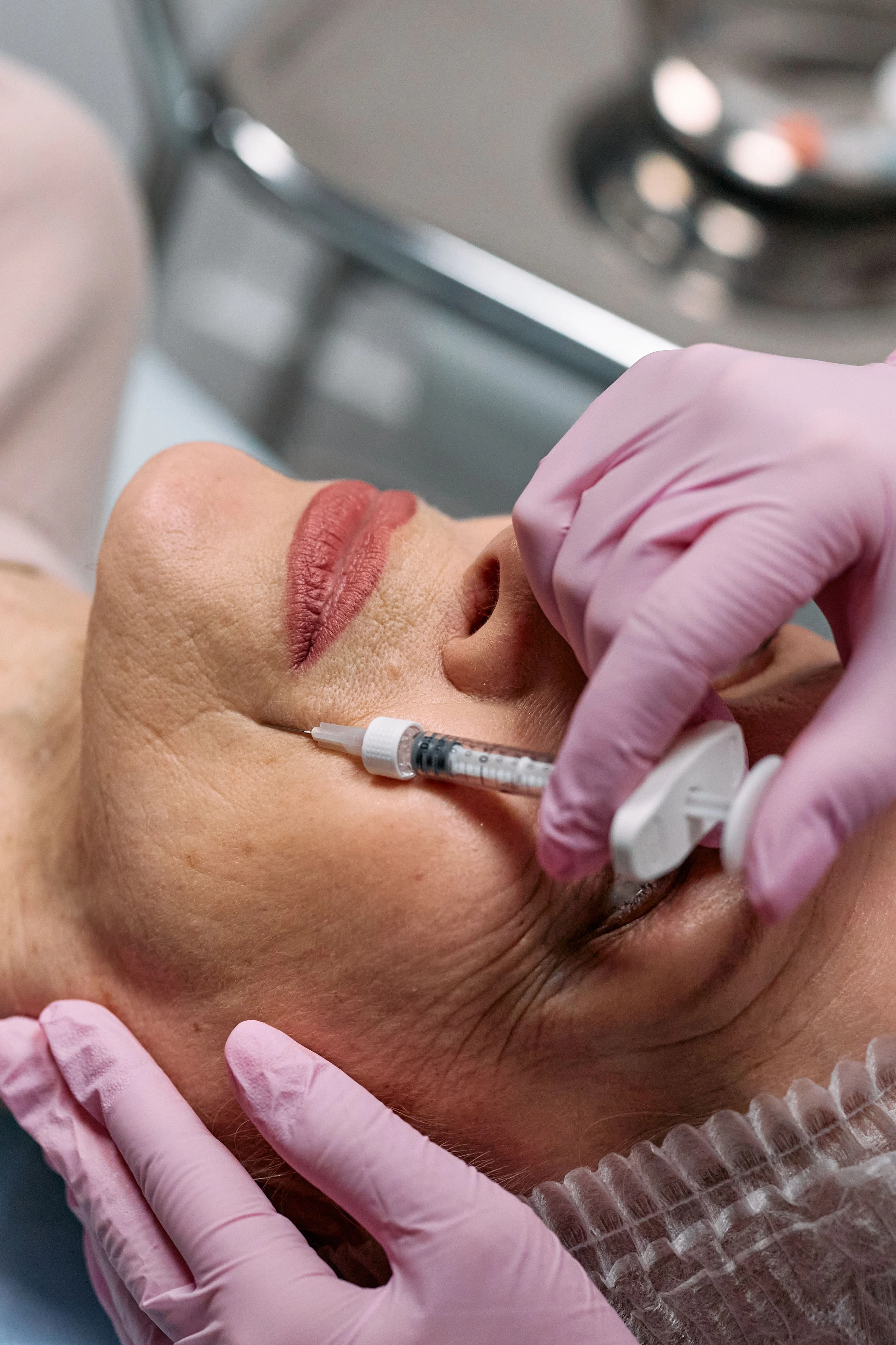 Gloved injector administering a cosmetic injection to a patient's face