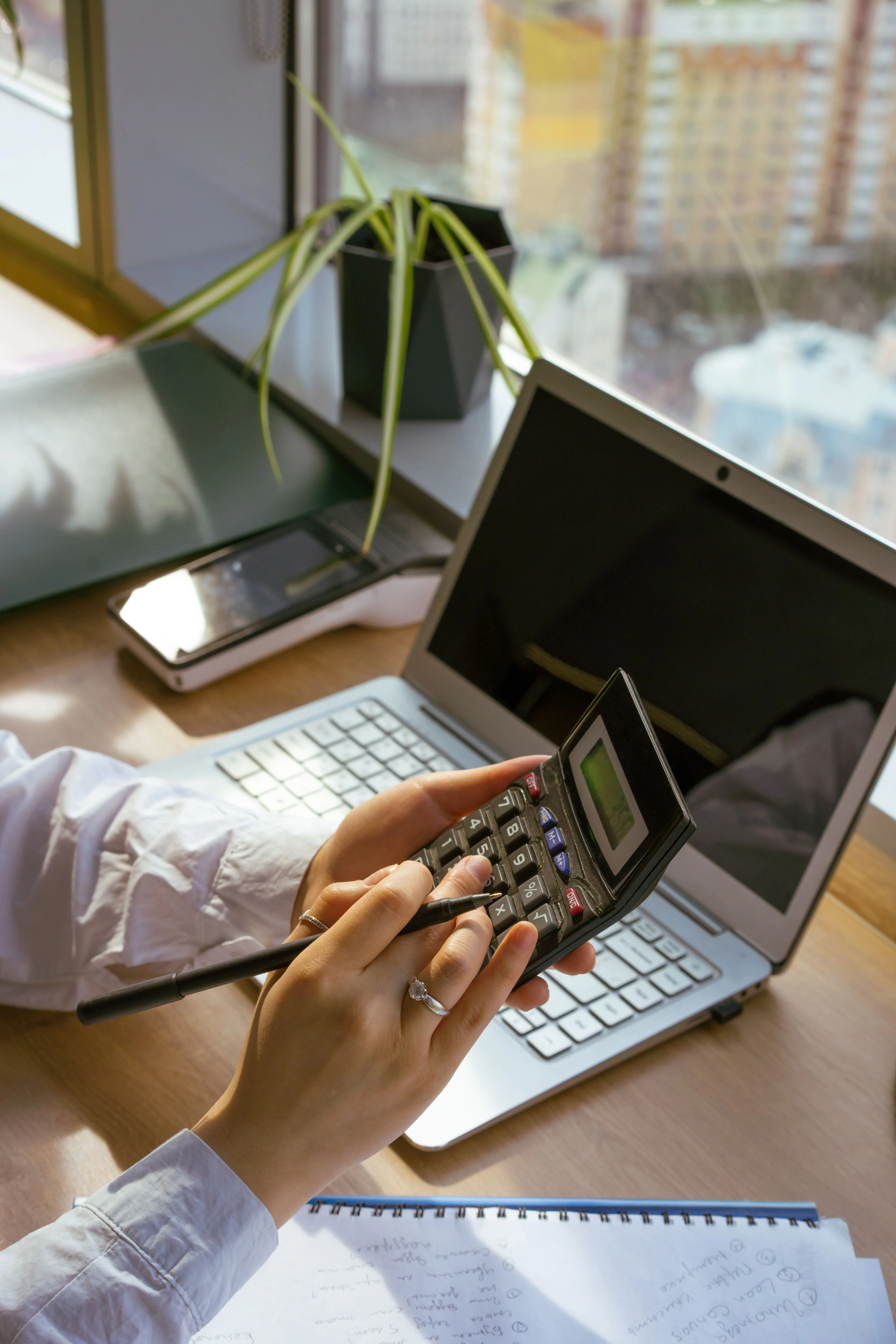 Person working through budget figures with a calculator and laptop
