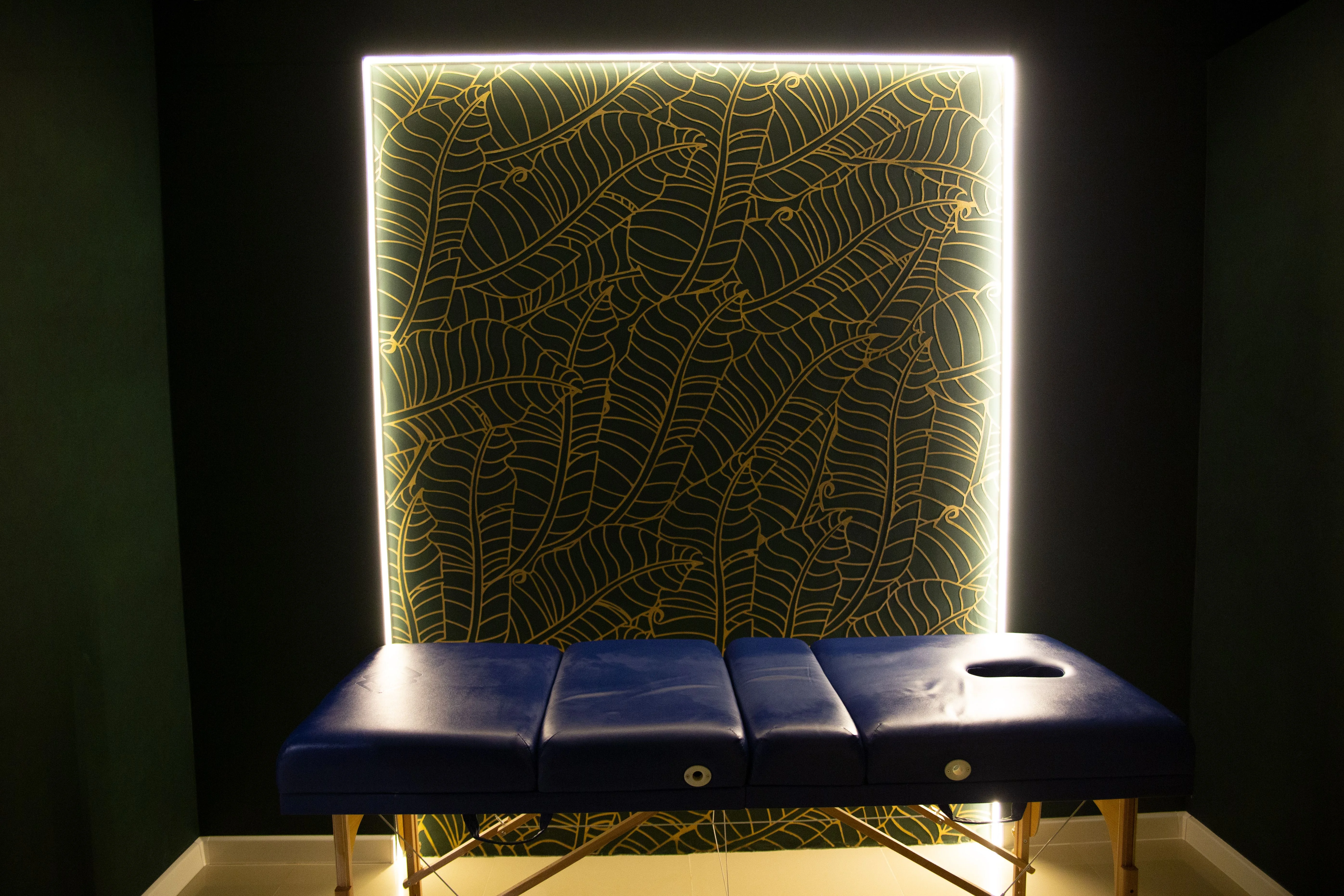 Spa massage room with a treatment table and illuminated wall panel
